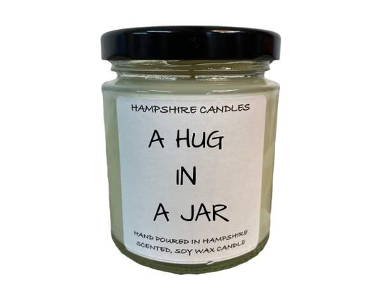 "Hug in a Jar candle in a 190ml clear glass jar with a black lid, beautifully packaged in a gift box."